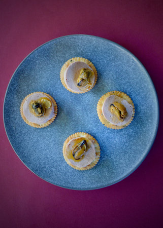 Liverwurst and smoked mussels with cracker biscuits  on a blue plate on a pink background