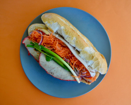 A Vietnamese pork roll with vegetables on a blue plate on an orange backgroundの写真素材