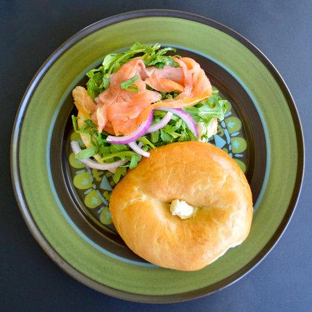 Bagel with smoked salmon and arugula salad on plateの写真素材