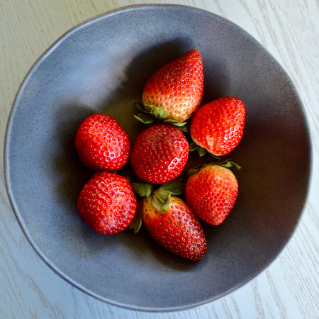 Strawberries in a bowl on a wooden table. Top view.の写真素材