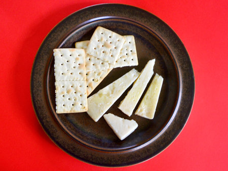 Cheese crackers on a plate on a red background, top view