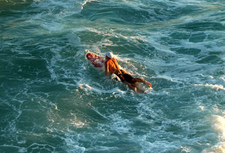 surfer paddling to a waveの写真素材