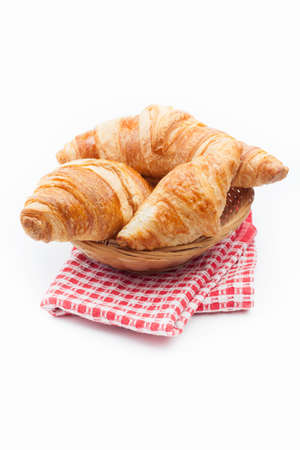 Fresh and tasty croissant on red checkered napkin over white backgroundの写真素材