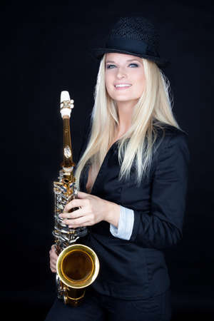 Beautiful young girl with saxophone on black backgroundの写真素材