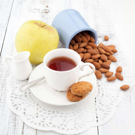 Breakfast with fresh homemade cookies, apple and nuts with cup of tea on wooden tableの写真素材