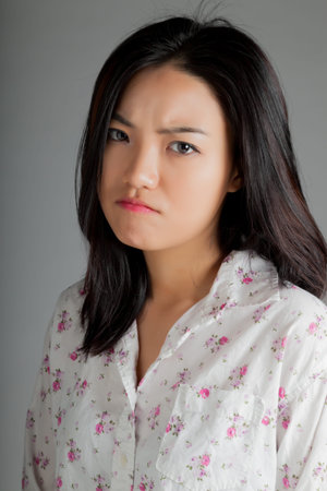 Attractive asian girl in her twenties isolated on a plein background shot in a studio