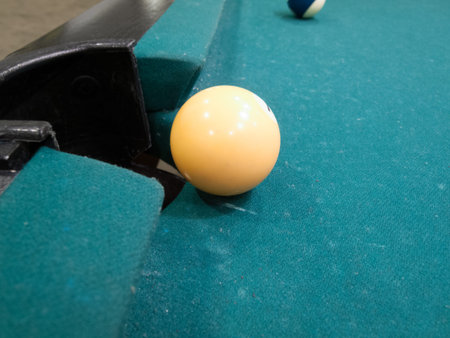 Yellow ball at the edge of hole on the pool table