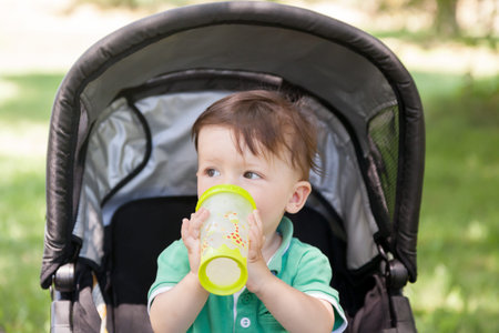 Boy sitting in a pram and drinking water