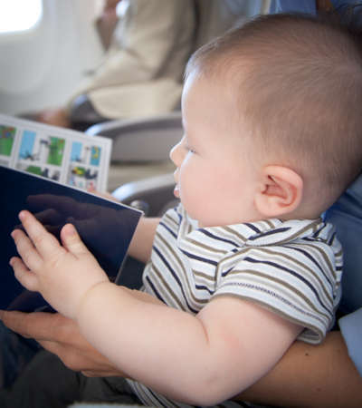 Baby boy reading a book in an airplaneの写真素材