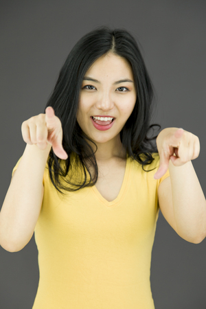 Asian young woman pointing at you from both handsの写真素材