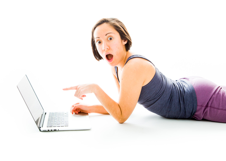 Young woman looking shocked with using laptopの写真素材