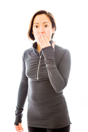 Young woman with hand over her mouth and shockの写真素材