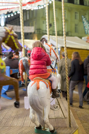 Girl enjoying carousel ride in an amusement park, Dinan, Cotes-D'Armor, Brittany, France 2011-12-25 12:03:46 PMのeditorial素材