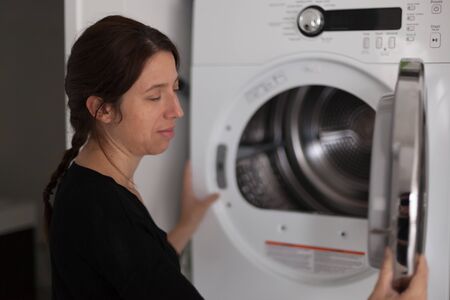Profile of mid adult woman using a washing machineの写真素材