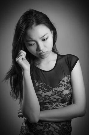 Attractive asian girl in her twenties isolated on a plain background, black and white image shot in a studioの写真素材