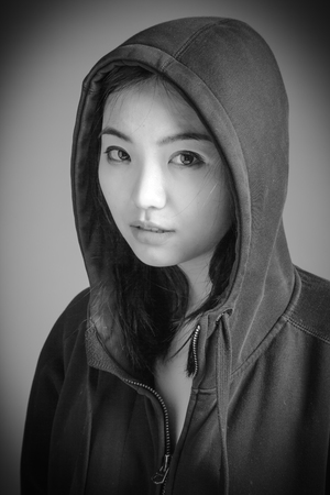 Attractive asian girl in her twenties isolated on a plain background, black and white image shot in a studioの写真素材