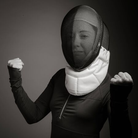 Female fencer in fencing mask with punching the airの写真素材