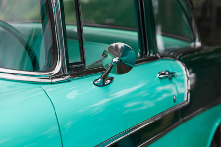 Close-up of wing mirror of a turquoise shiny classic vintage car