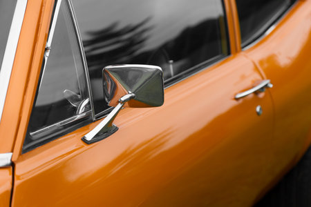 Close-up of wing mirror of an orange shiny classic vintage carの写真素材