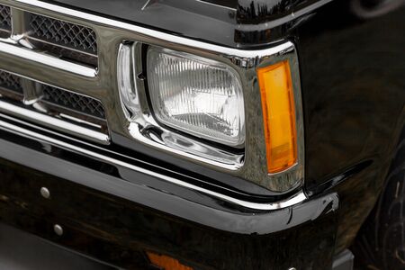 Close-up of right headlight of a black shiny classic vintage carの写真素材