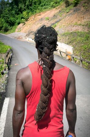 Adult, Adults Only, Black Hair, Braided Hair, Casual Clothing, Colour Image, Contemplation, Day, Decisions, Diminishing Perspective, Dirty, Dreadlocks, Green, Hill, Lifestyles, Long Hair, Males, Men, On The Move, One Man Only, One Person, Outdoors, Peopleの写真素材