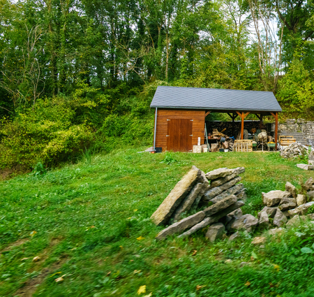 Small wooden hut with trees behind, piles of rocks in foreground. belgium europeの写真素材
