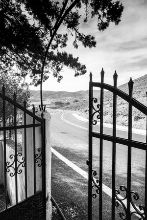 View of empty mountain road through open gate , Crete, Greece