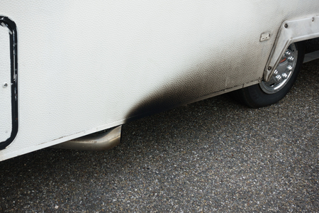 Low section of parked bus with exhaust pipe and tyreの写真素材