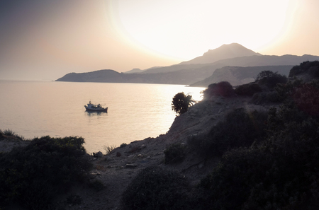 Silhouette of boat and mountain on Milos Island Greeceの写真素材