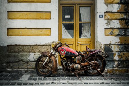 Old rusty motorbike in front of houseの写真素材