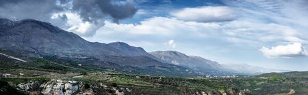 Scenic view of mountains and landscape against sky with cloudsの写真素材
