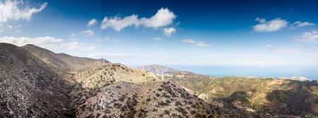 Majestic view of mountains with windmills against skyの写真素材