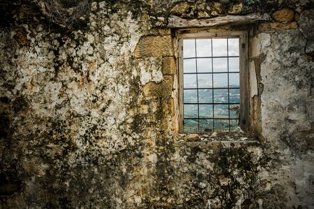 View of agricultural field through window grill of a weathered wallの写真素材