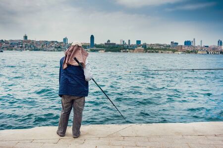 Man fishing on the sea with cityscape in the background, Istanbulの写真素材