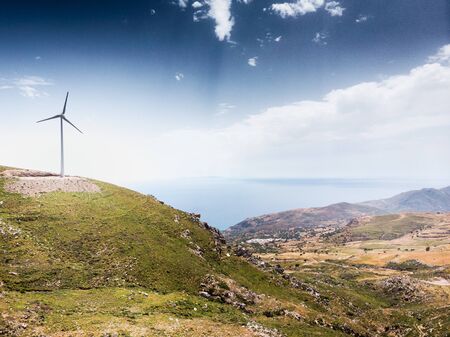 Windmill on mountain against sky with scenic landscapeの写真素材