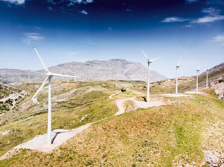 Wind turbines on mountain by against skyの写真素材
