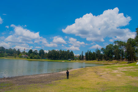 Man standing on the shore of the lake. Blue sky and white clouds.の写真素材