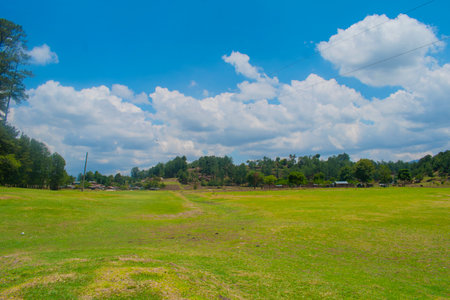 Green field with blue sky and white clouds in the countryside at Guatemalaの写真素材