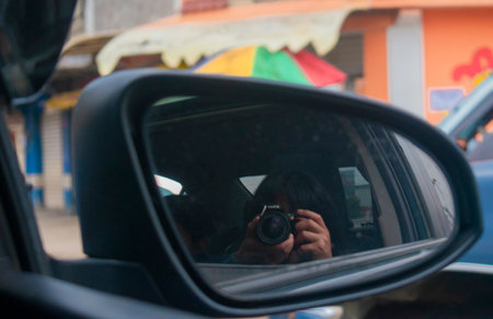 Reflection in the side mirror of a car with a digital cameraの素材