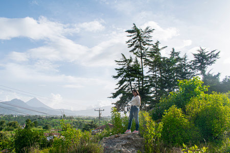 Young woman standing on the top of the mountain and looking at the viewの写真素材
