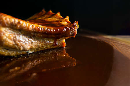Roasted pork ribs on a wood base with salt, reflective barbecue sauce and copy spaceの写真素材