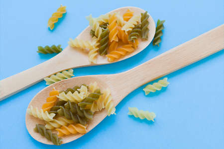 spoons full of rotini over a blue backgroundの写真素材