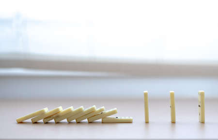 Concept of social distancing explained with dominoes, with some of them fallen but others spread enough to not fallの写真素材