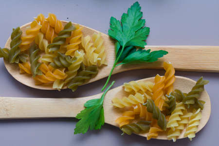 two wooden spoons with raw vegetable rotini and rosemaryの写真素材