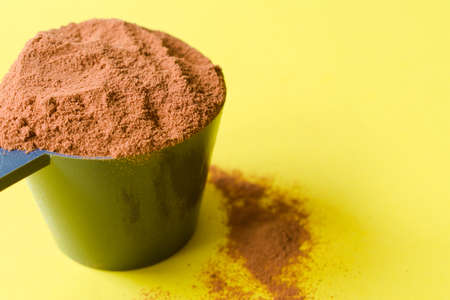 Spoon with chocolate protein powder. Yellow backgroundの写真素材