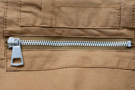 Close-up of a metallic zipper closed pocket, horizontal, in a brown color piece of fabricの写真素材