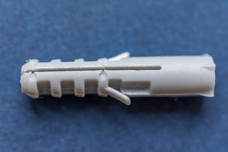 Close-up of a gray plastic wall plug over a dark blue background