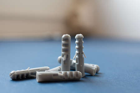 Close-up of a bunch of gray plastic wall plugs on a blue cardboard, with a blurry background