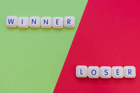 Winner and loser words made with board game letters, with the winner on the green side and the loser on the red side of the image. Competitors and rivalry conceptsの写真素材