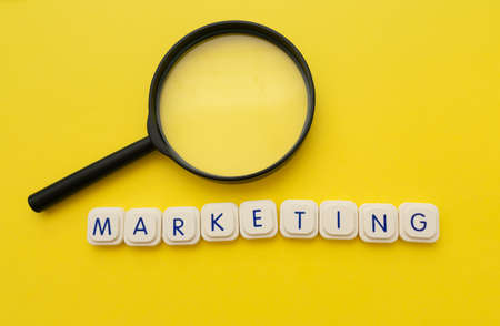 Marketing word and a magnifying glass over a yellow background. Marketing concept.の写真素材